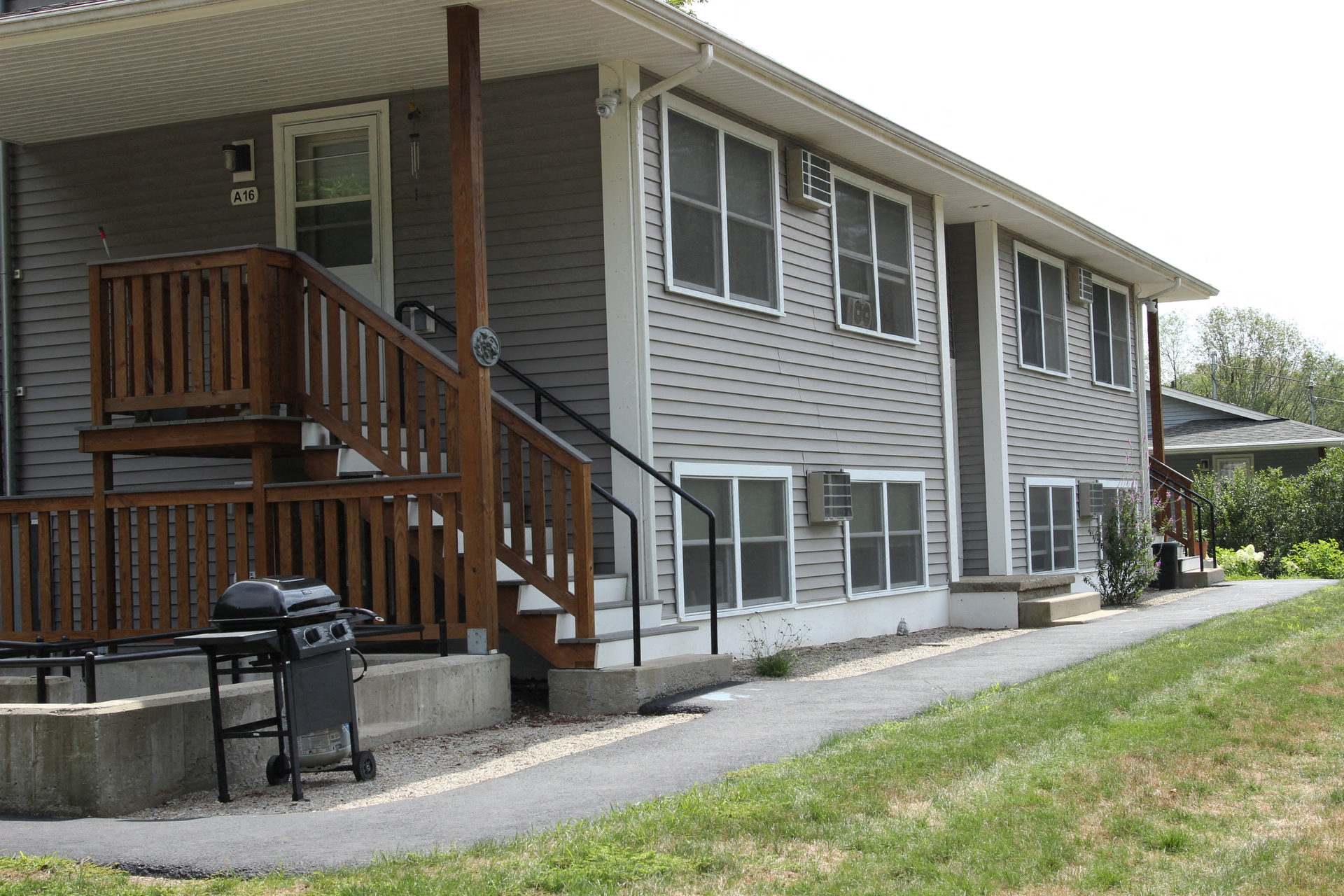 the front of the house with a grill on the sidewalk
